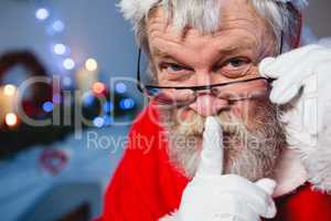 Santa claus keeping his finger on lips at home