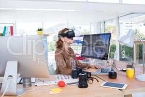 Female executive working on laptop while using virtual reality headset