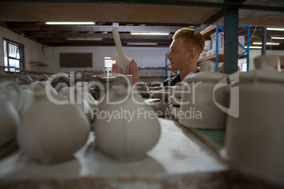 Male potter examining a earthenware equipment