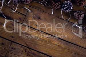 Christmas light and pine cones on wooden plank