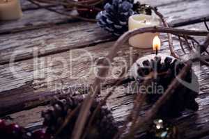 Lit candles and christmas decoration on wooden plank