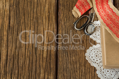 Wrapped gift, ribbon and scissors on wooden plank