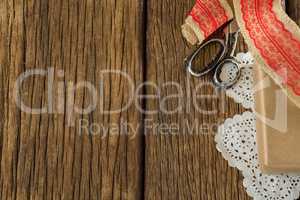 Wrapped gift, ribbon and scissors on wooden plank