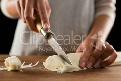 Woman slicing dough on chopping board