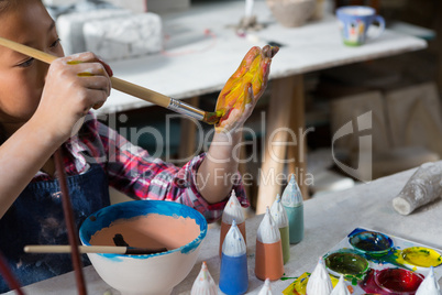 Girl painting her hand with paint brush