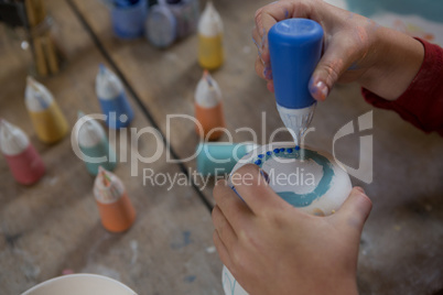 Hands of boy decorating mug with paint