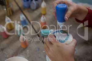 Hands of boy decorating mug with paint