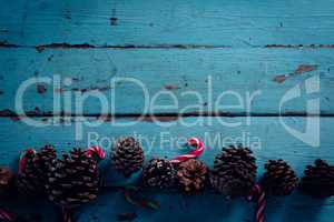 Pine cone and candy cane arranged on wooden plank