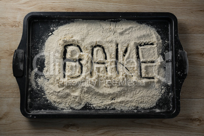 The word bake written on flour on a baking tray