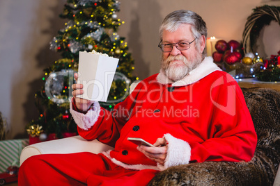 Santa Claus using mobile while having popcorn