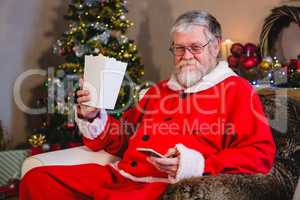 Santa Claus using mobile while having popcorn