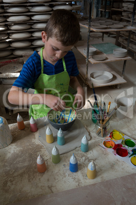 Boy painting a bowl in pottery shop