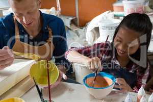Male potter and girl painting bowl