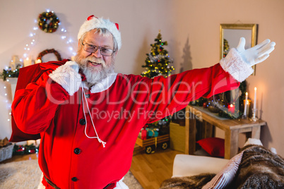 Santa claus doing welcoming gesture while carrying his gift sack