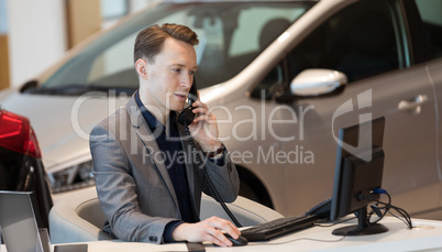 Sales talking on phone while using computer