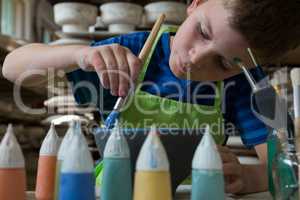 Boy painting a bowl in pottery shop