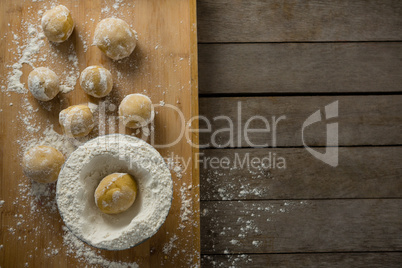 Dough ball placed over flour on a wooden table