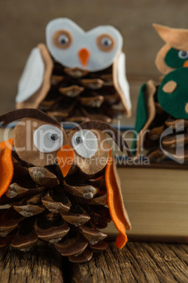 Owl decorated with pine cone and book stack on wooden table