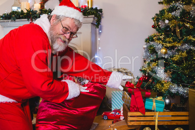 Santa Claus arranging gifts near christmas tree
