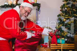 Santa Claus arranging gifts near christmas tree