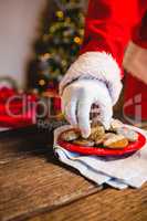 Mid-section of Santa Claus selecting cookie of plate