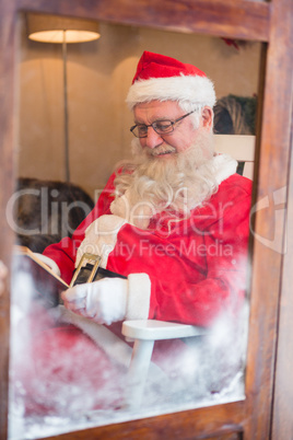 Smiling santa claus reading novel during christmas time