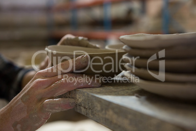 Male potters hand examining a bowl