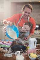 Mother and daughter preparing cup cake in kitchen