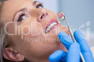 Doctor holding angled mirror by woman at medical clinic