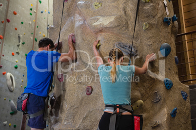 Rear view of athletes rock climbing in studio