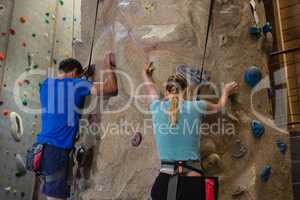 Rear view of athletes rock climbing in studio