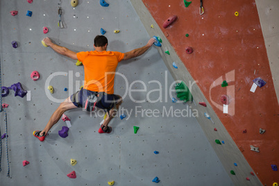 Rear view of athlete rock climbing in health club