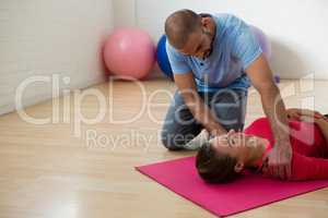 Yoga instructor guiding student in exercising at club