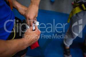 hand of woman taking chalk powder from trainer in gym