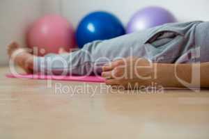 Low section of woman exercising while lying on mat