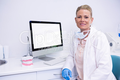 Dentist working while sitting by computer at medical clinic