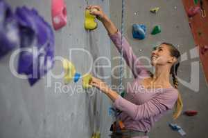 Smiling athlete climbing wall in health club