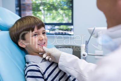 Smiling boy looking at dentist while sitting on chair