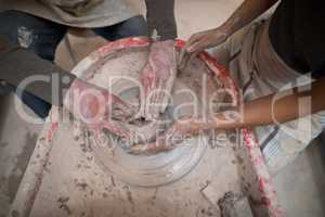 Mid section of male potter assisting female potter
