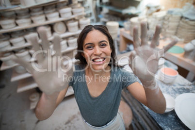 Portrait of female potter showing her hands with clay