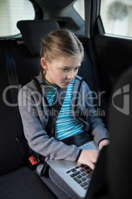 Teenage girl using laptop in the back seat