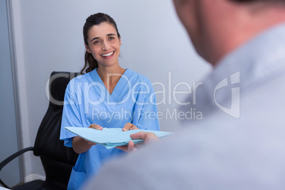 Happy doctor giving file to patient