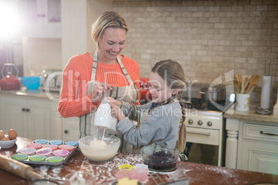 Mother and daughter mixing eggs and wheat flour in a bowl