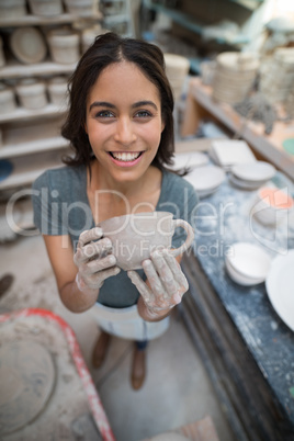 Portrait of female potter holding clay cup
