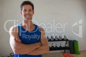 Portrait of confident athlete with arms crossed standing in gym