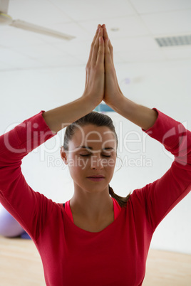 Woman meditating while doing tree pose in yoga studio