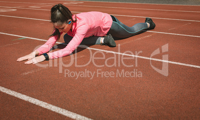 Woman performing stretching exercise on a race track