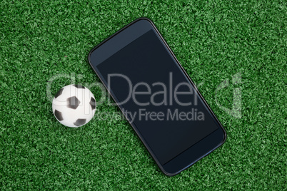 Football and mobile phone on artificial grass