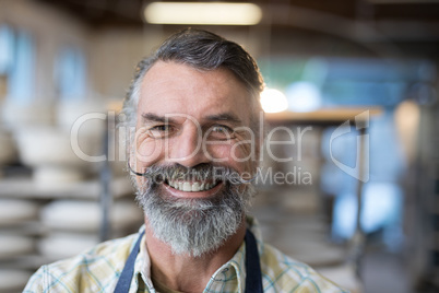 Happy male potter standing in pottery workshop