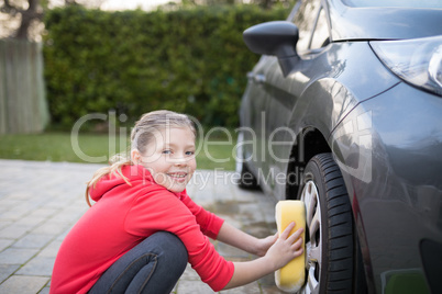 Teenage girl washing a car on a sunny day